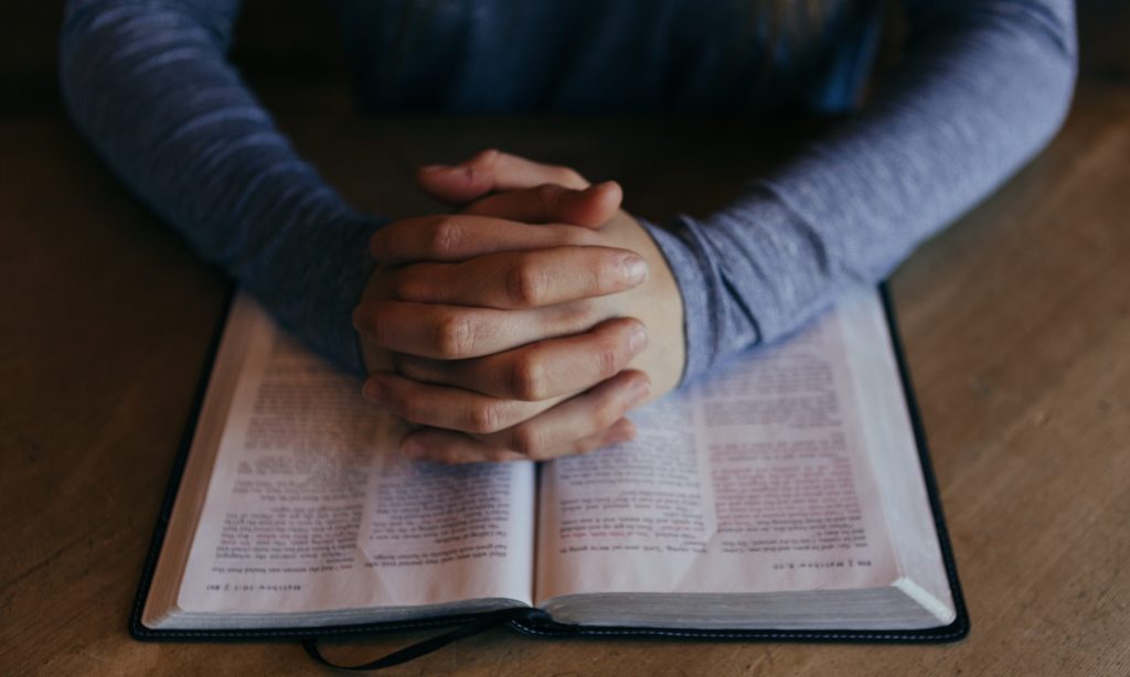 Hands pray on bible