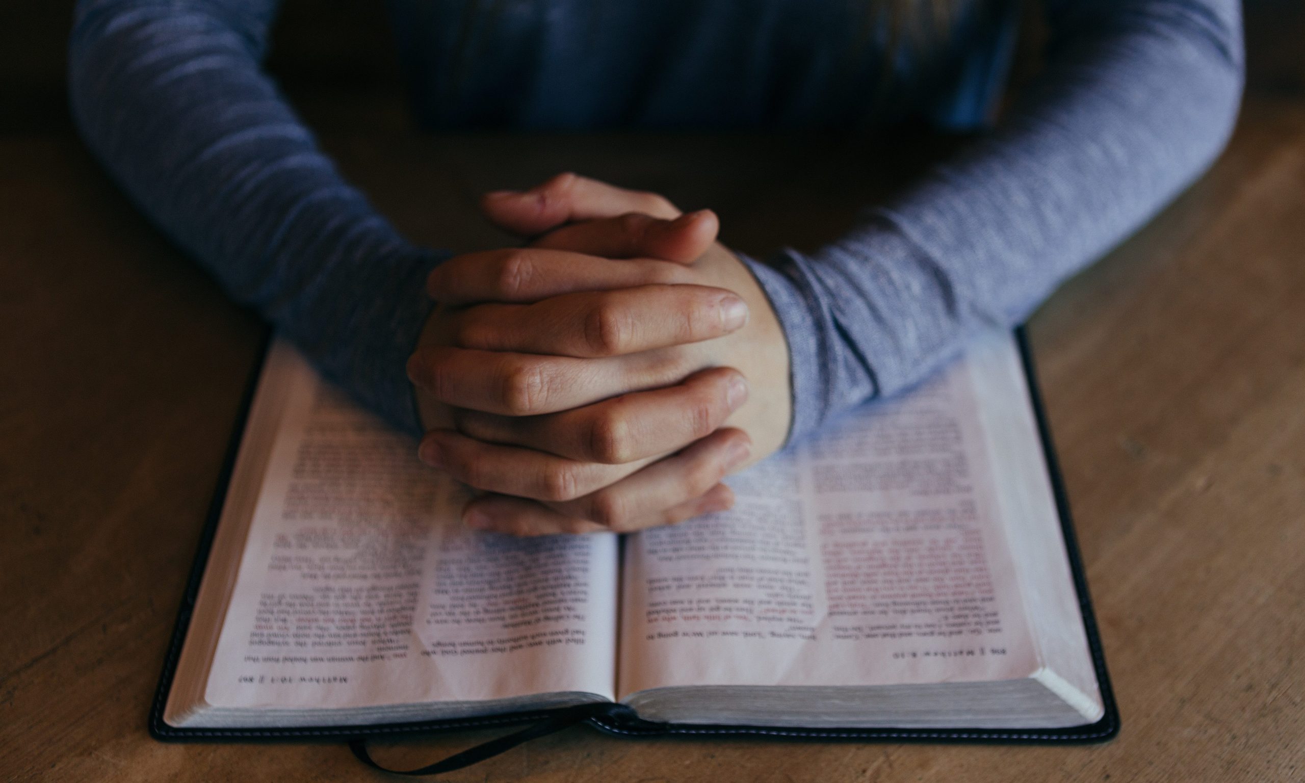 Hands pray on bible